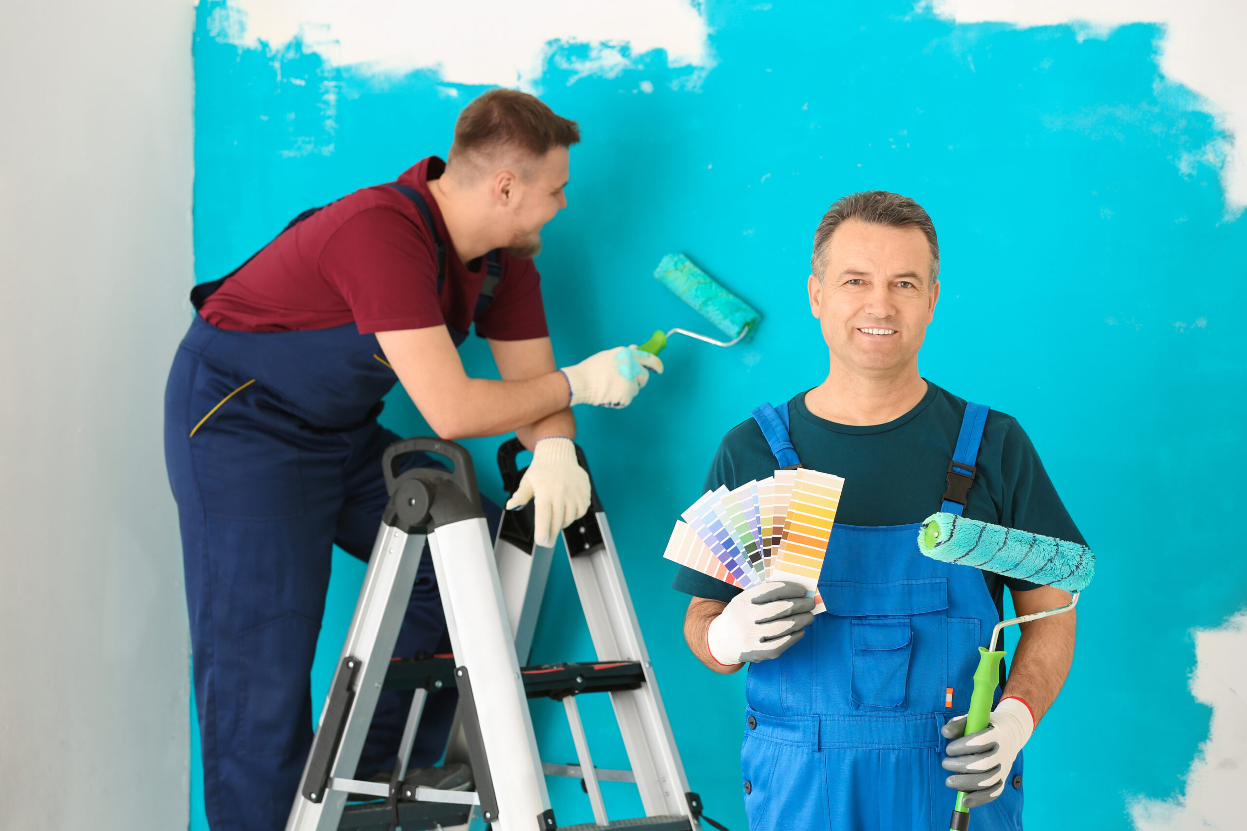 Paint Services male painter in uniform with color palette samples and roller brush indoors