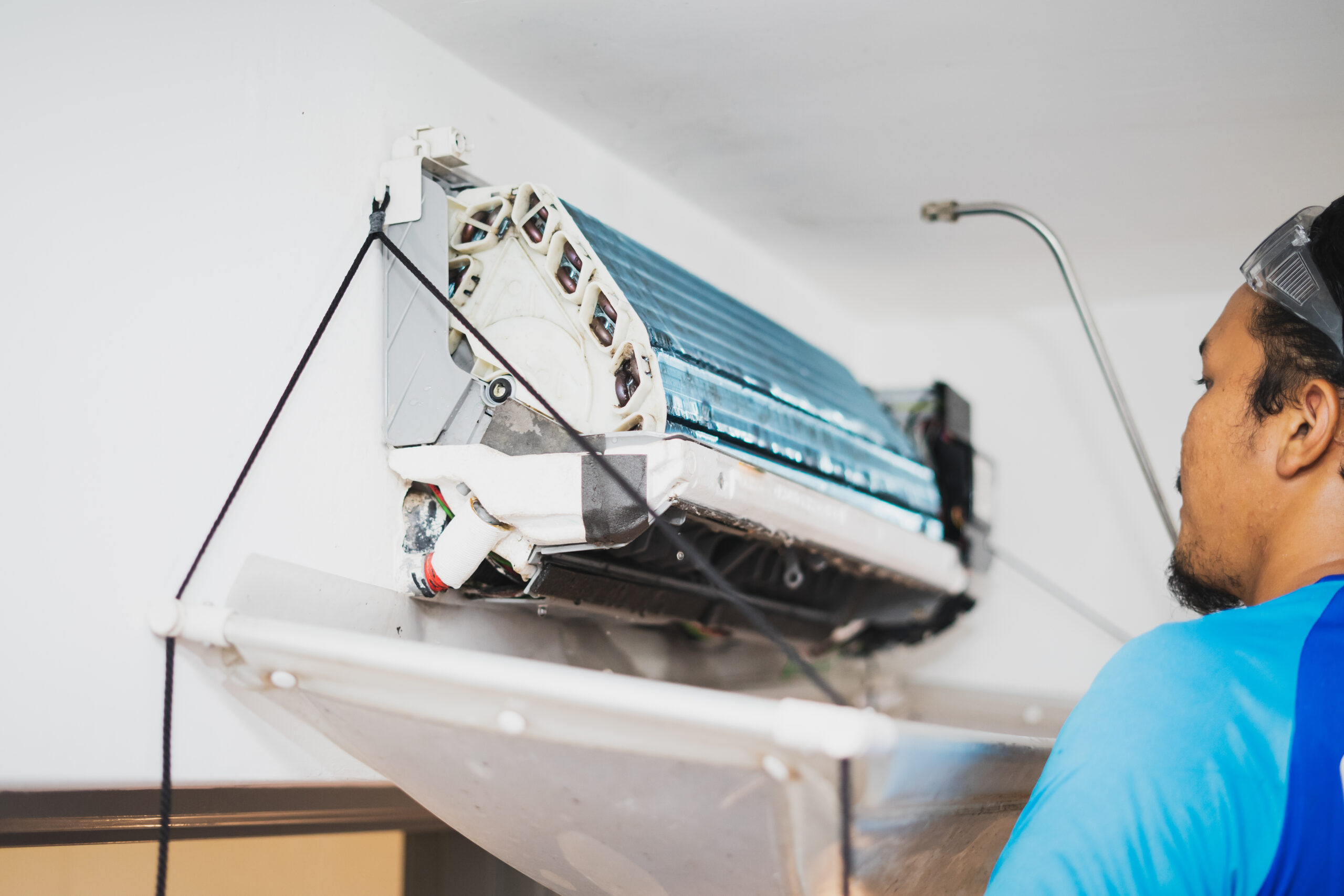 AC Services male technician cleaning air conditioner indoors