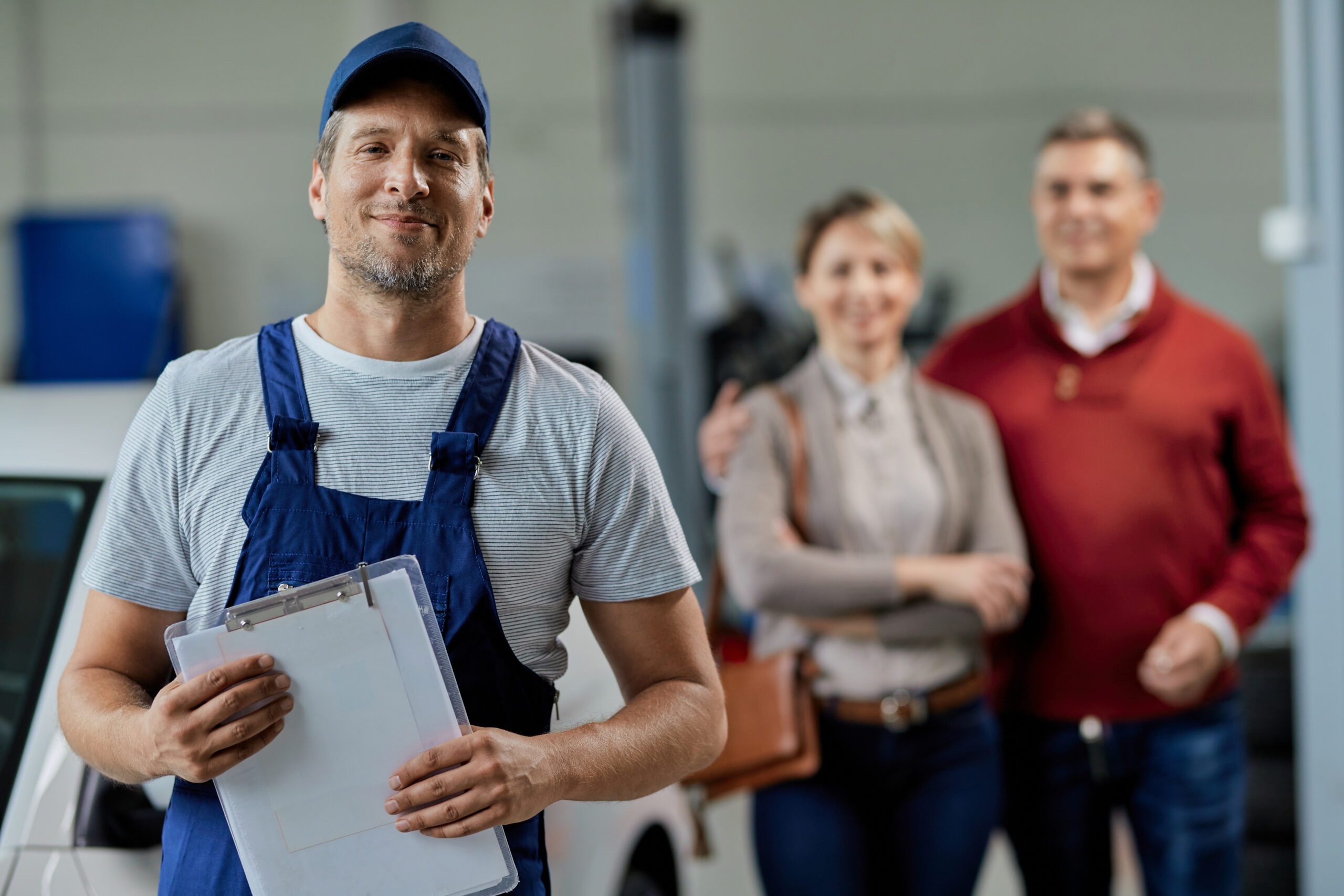 About portrait of happy car mechanic with his customers in the backgro